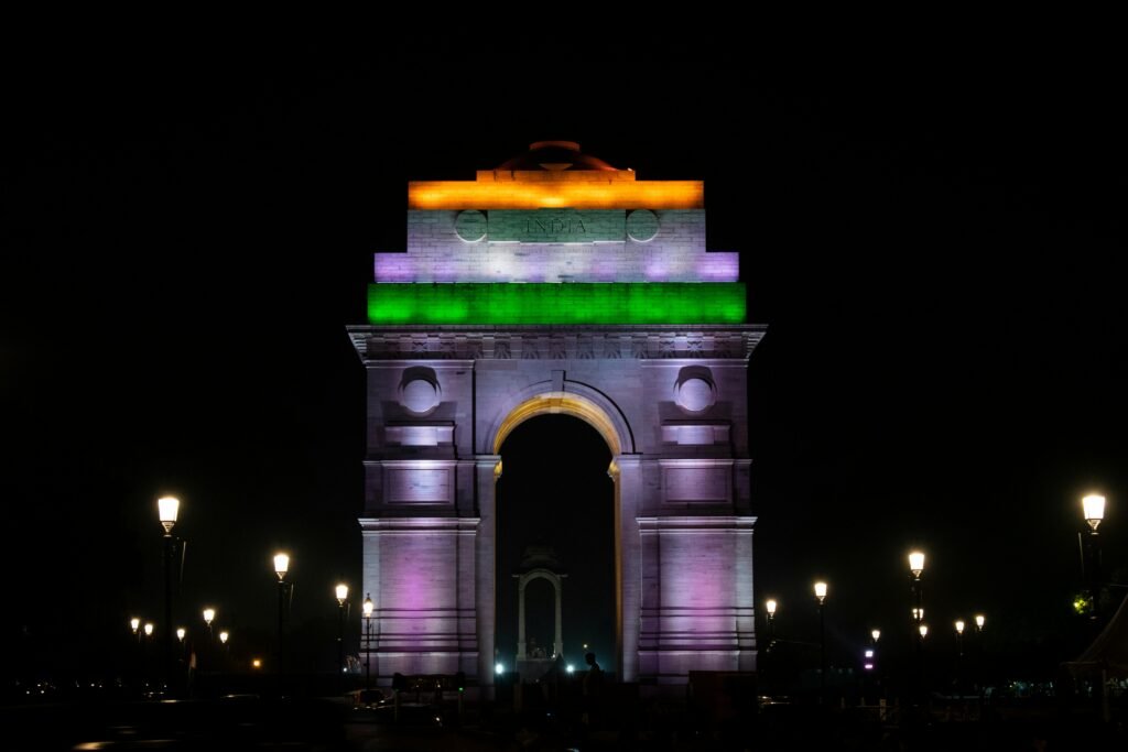 Brightly lit India Gate in New Delhi captured at night, showcasing vibrant lights and urban atmosphere.