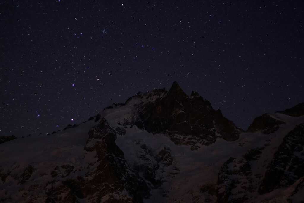 A breathtaking view of a starry night over snowy mountains, capturing the tranquility and beauty of the winter landscape.