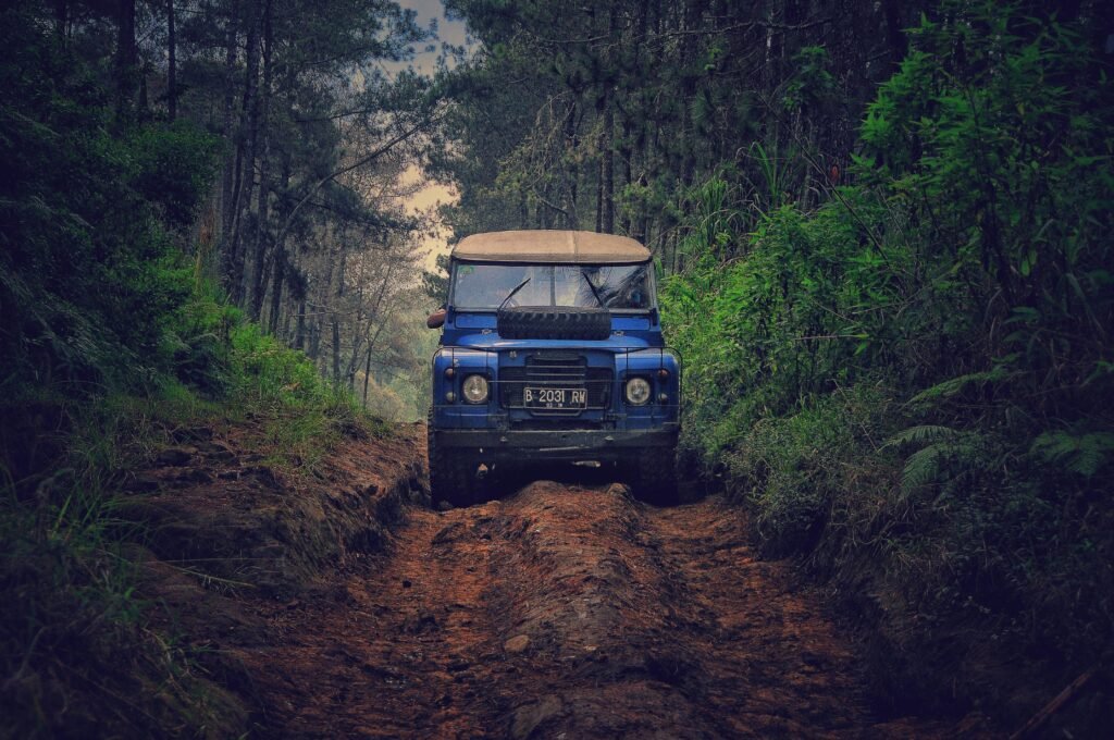 Off-road vehicle traversing a rugged dirt path through lush forest in Parongpong, Indonesia.